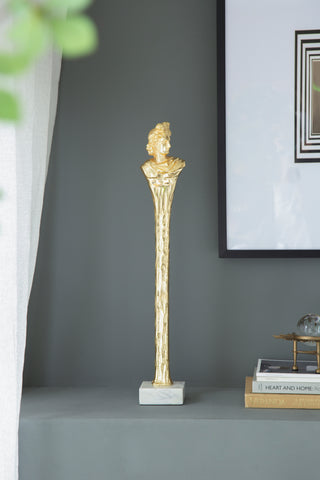 Elongated gold Roman statue on white marble base