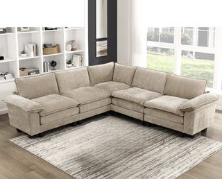 Beige sectional sofa in a living room with a rug and window view.