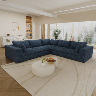 Modern living room with a large blue sectional sofa, white coffee table, and decorative items.