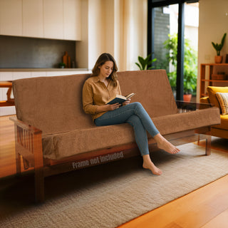 Woman reading a book on a brown futon in a living room.