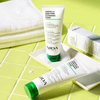 Two tubes of NIDA Centella Deep Pore Cleansing Foam on a green and white checkered surface.